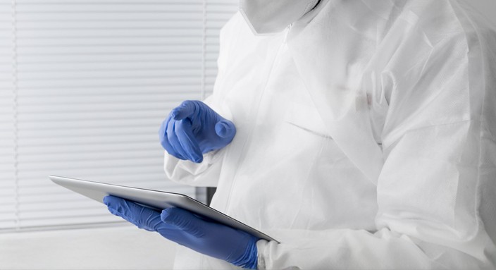 Reinraumtechniker in Schutzkleidung nutzt ein Tablet zur Dokumentation von Prozessdaten.